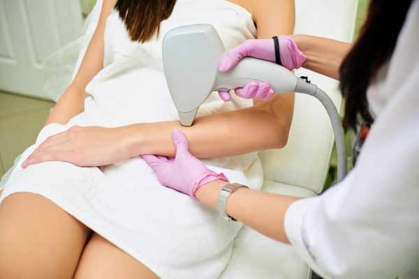 A cosmetologist carries out a procedure for laser hair removal from the body of a girl. Laser hair removal. Cosmology. Hand hair removal